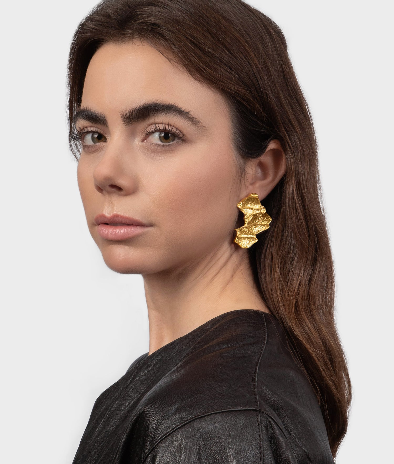 Mujer modelo vistiendo unos pendientes de plata chapados en oro con diseño orgánico