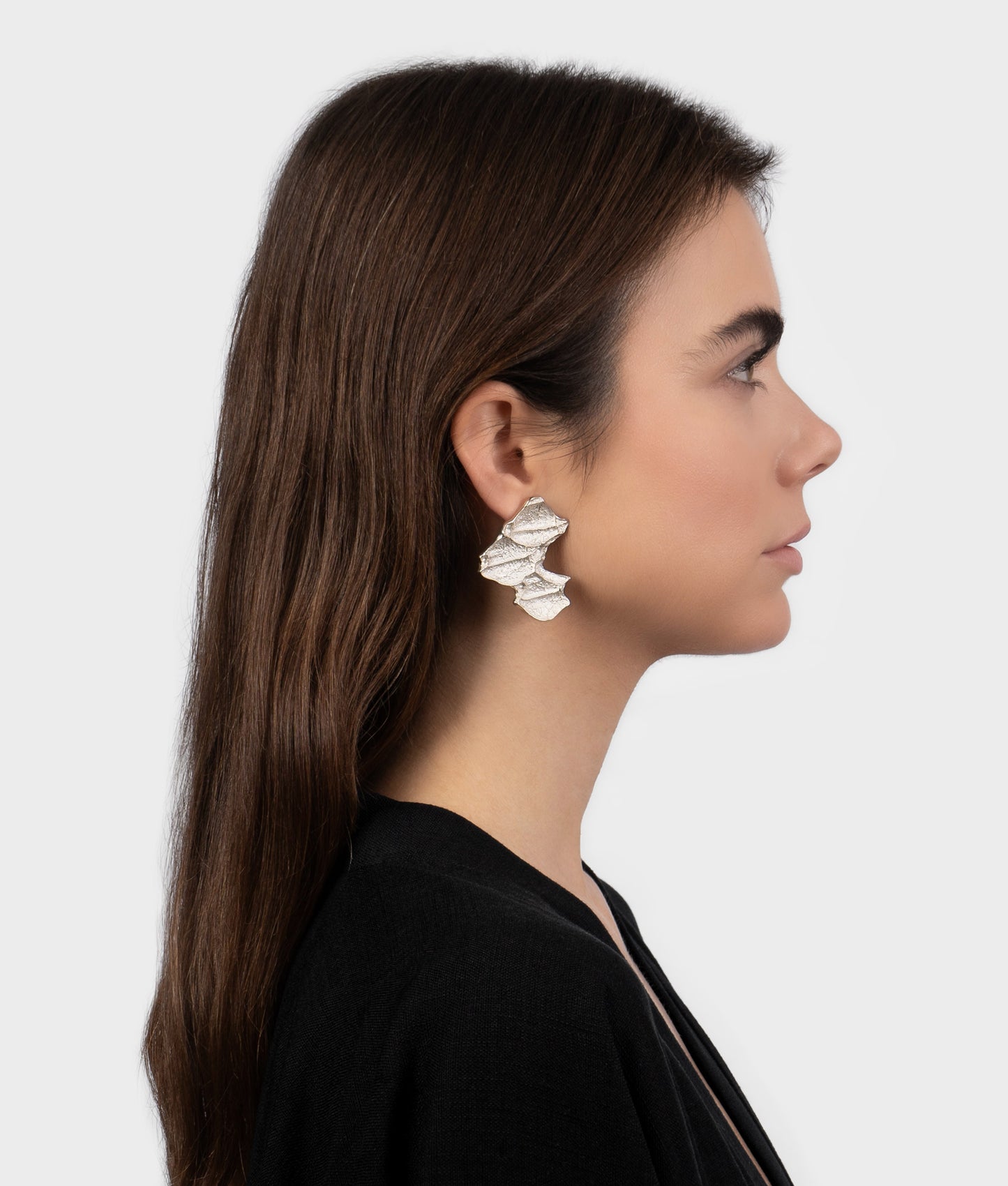 Mujer modelo vistiendo unos pendientes de plata con diseño orgánico en forma de hojas