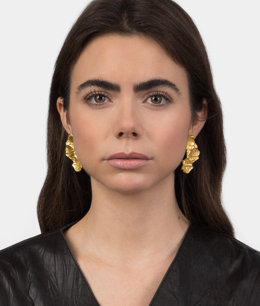 Mujer modelo vistiendo unos pendientes de plata chapados en oro con diseño orgánico